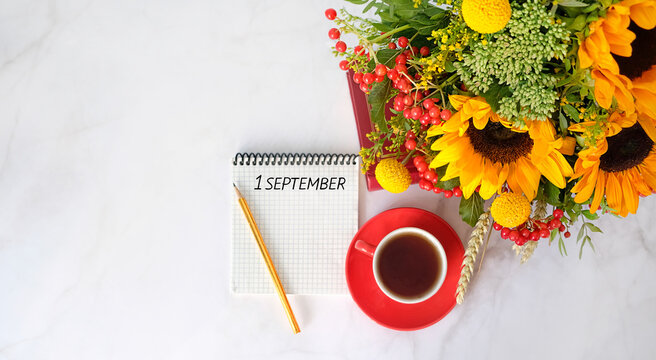 1 September text in notebook, pencil, coffee cup and flowers bouquet with sunflowers on marble background. Autumn season beginning, september month calendar concept. back to school. flat lay