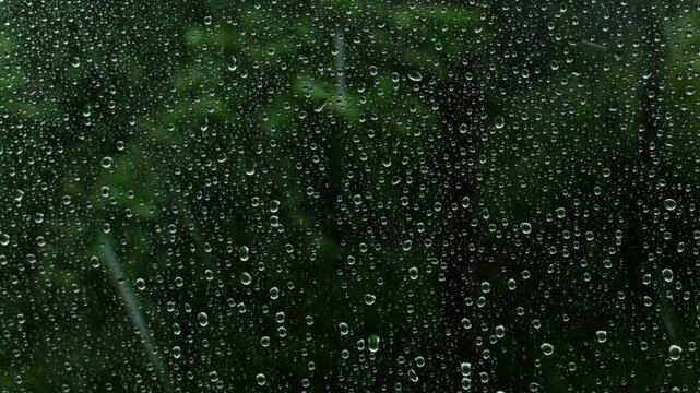 Water droplets trickling down window glass during a severe hailstorm with heavy rain outside