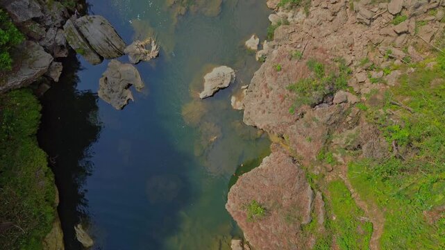 Aerial view of the river flowing past the rocky cliffs and lush vegetation at Sri Gethuk Waterfall in Yogyakarta, Special Region of Yogyakarta, Indonesia.