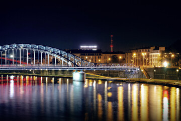 Fototapeta premium Horizontal night riverside photo of Jozef Pilsudski bridge lights reflected on water real life photography
