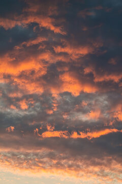 Vertical dramatic sunset cloudscape photo with orange and blue tones real life photography