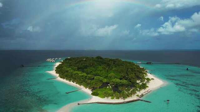 Aerial view of Meedhupparu island with lush tropical vegetation, white sandy beaches, and overwater villas surrounded by turquoise lagoon waters in Raa Atoll, Raa Atoll, Maldives.