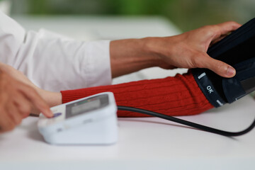 Fototapeta premium Healthcare professional monitoring patient's blood pressure using a digital sphygmomanometer during a medical checkup, focusing on prevention and early detection of hypertension