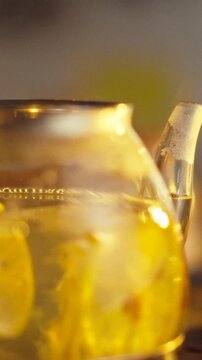 Lemon slices and ginger pieces rest in clear teapot filled with water, creating bright beverage, close-up captures lemon fragments floating, presenting food-preparation view focused on healthy eating