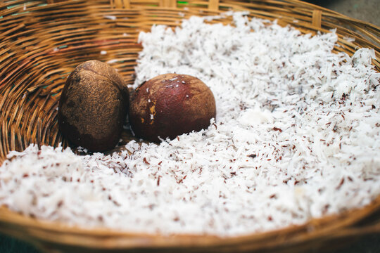 Close-up of two coconuts and shredded coconut in a woven basket, India. Rustic, textured composition.