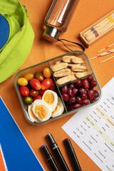 Healthy school lunchbox with boiled eggs, cherry tomatoes, grapes and crackers next to weekly class...