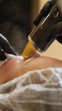 Professional beautician applying cleansing mask on female client's face. Close-up of female face during youth restoration and facial rejuvenation procedure  - Vertical Video