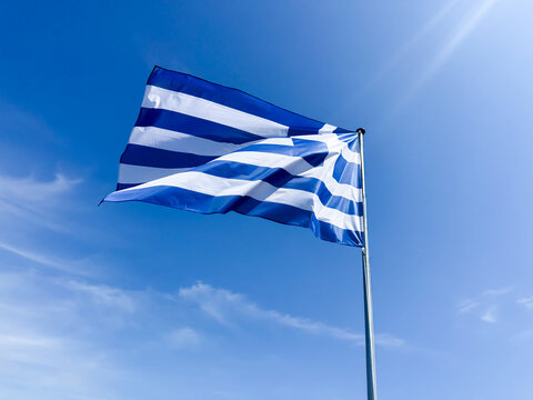 View of the national flag of Greece waving against a clear blue sky in Zaandam, North Holland, Netherlands.