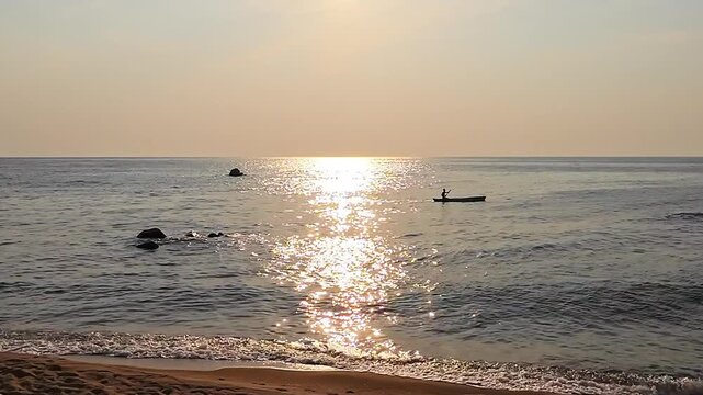 Silhouetted paddler in a traditional wooden dugout canoe glides across glittering Lake Malawi at golden sunrise, creating a serene African scene.