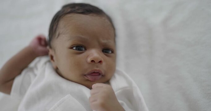 Closeup portrait of african happy baby talk lying play on bed over white background Healthy newborn child looking moving. Family love newborn healthcare medical concept.