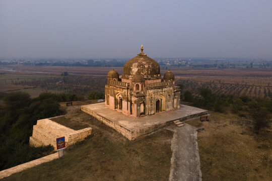 View of Maqbara Khair un Nisa with its historic dome and arched facade set on a hilltop overlooking the surrounding landscape in Dina, Punjab, Pakistan.