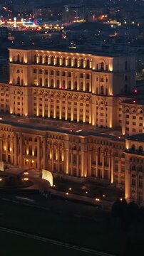 Aerial view of Palace of the Parliament in Bucharest Romania at night with illuminated architectural facade.