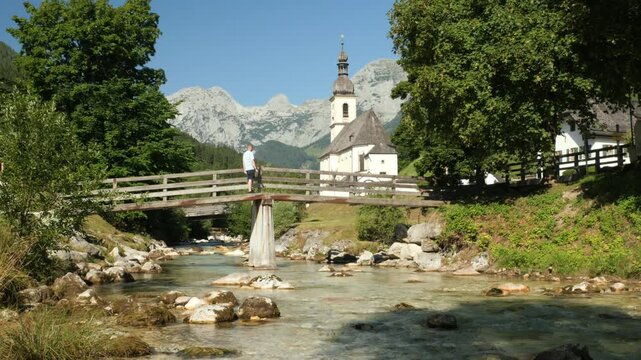 Scenic view of a man crossing a bridge toward the historic church in Ramsau, Bavaria, Germany