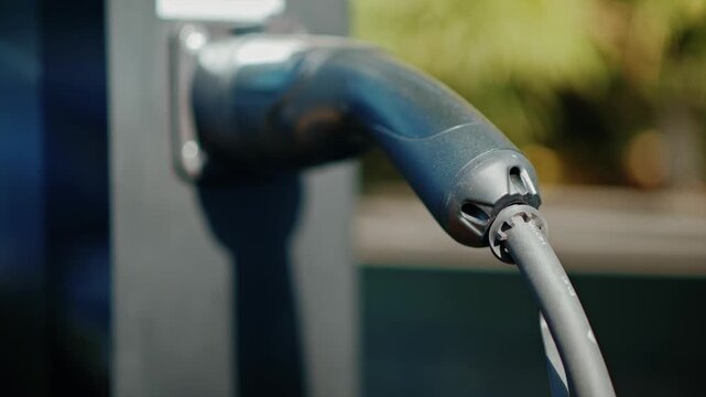 Electric vehicle charging cable connected to station power point for sustainable transportation refueling.
