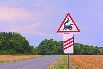 Railway Crossing Warning Sign on Rural Road at Sunset © physyk