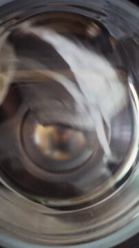 White laundry tumbles in a side-loading washing machine with a clear window, the drum rotating as clothing is cleaned, showing routine housework and the function of a modern appliance