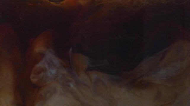 4K Extreme close-up macro shot of fresh milk pouring into black coffee creating swirling liquid effect, iced latte, coffee preparation, creamy texture and abstract background.