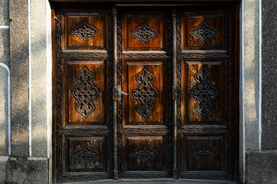Ornate carved wooden door with floral medallion patterns near Gur-e-Amir mausoleum in Samarkand. Traditional Uzbek woodcarving detail ideal for travel and cultural heritage projects.