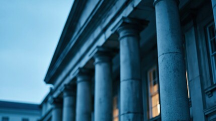 Fototapeta premium Low angle view of classical stone columns and windows of a grand building against twilight sky