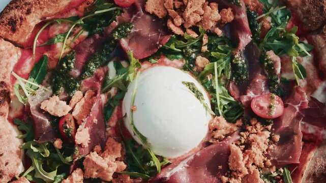 Fresh gourmet pizza topped with burrata cheese and bresaola beef on a wooden table.