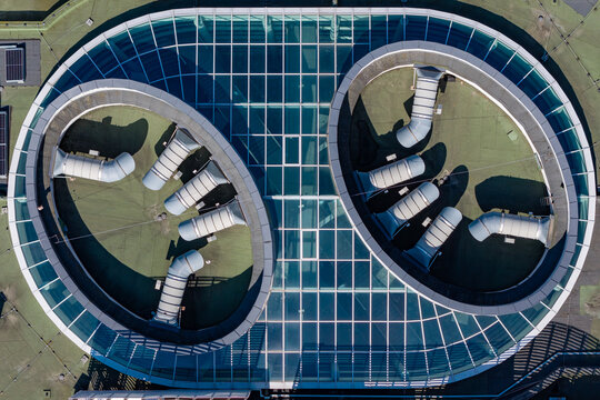 Aerial view of a modern and advanced university building with a glass atrium and ventilation ducts on the roof in Poland.