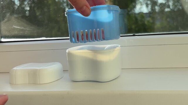 Elderly person hands using ultrasonic cleaner for denture maintenance at home, oral hygiene, dental care.