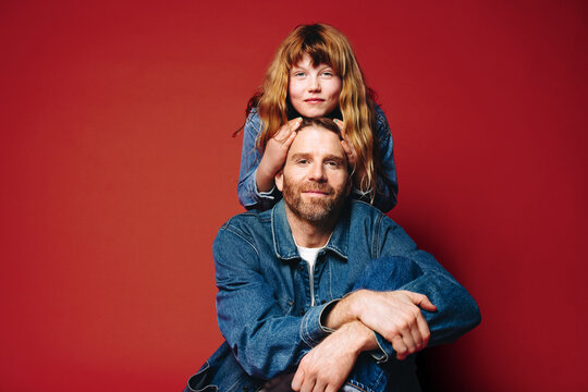 Father daughter closeness in a warm studio portrait against a red backdrop
