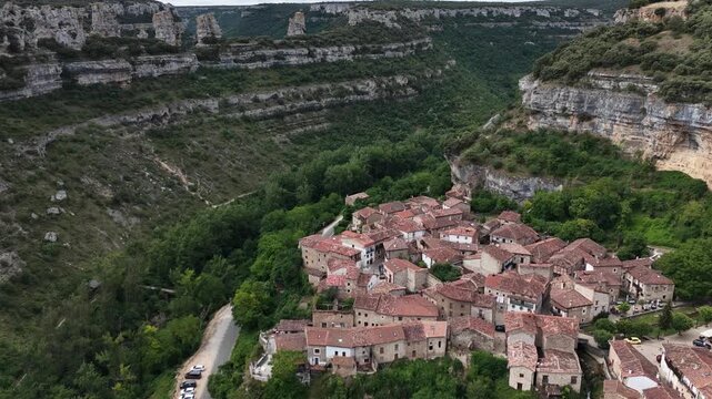 peaceful rural village scene with stone houses on rocky cliffs viewed from a low angle, looking up at the architecture and greenery in a serene setting, Risco los camellos