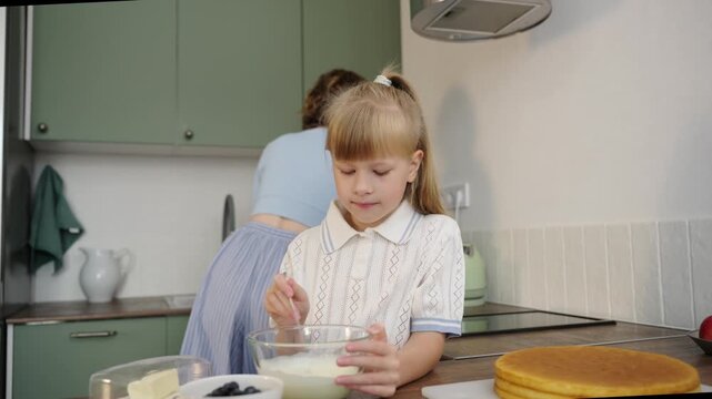 Mother and daughter bake layered cake together in cozy sunlit kitchen, 25 fps