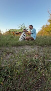 Young Man Training Dalmatian Dog Outdoors Park Giving Treat