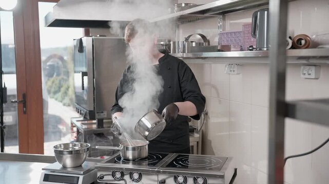 Young male chef cooking steaming sauce in a professional kitchen