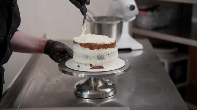 Professional pastry chef icing a layered cake with buttercream