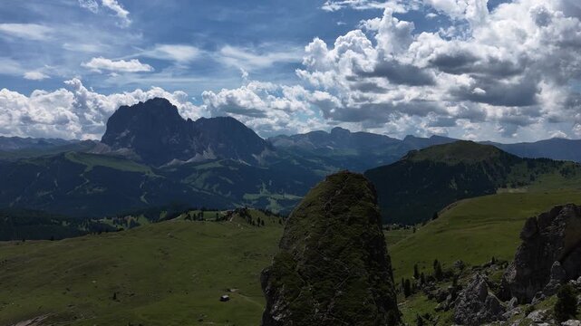 View of beautiful landscape in the Alps with fresh green meadows and mountain tops in the background on a sunny day with blue sky and clouds in summertime. Alpe di Cisles, Seceda Ridgeline, Dolomiti ,