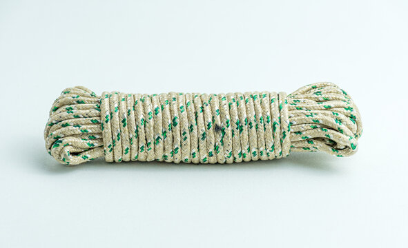 Rolled bundle of green and white twisted string rope isolated on white background