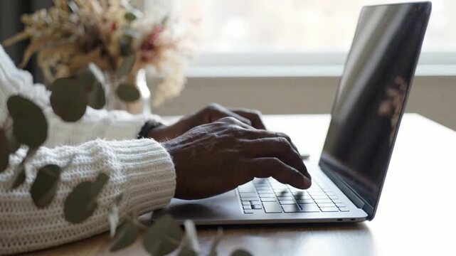 Person typing on laptop computer at home office desk, close-up of hands working on digital project, remote work and productivity concept