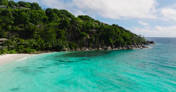 Coastline with turquoise waters and rocky formations meeting the white sandy beach. Seychelles, Mahe. Petite Anse.