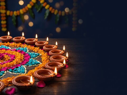 Diwali rangoli with colorful diyas and flower petals arranged in vibrant circle for festive background and decorative poster design