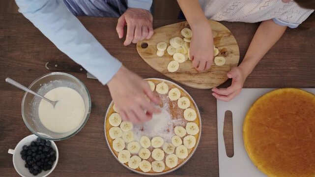 Mother and daughter bake layered cake together in cozy sunlit kitchen, 25 fps