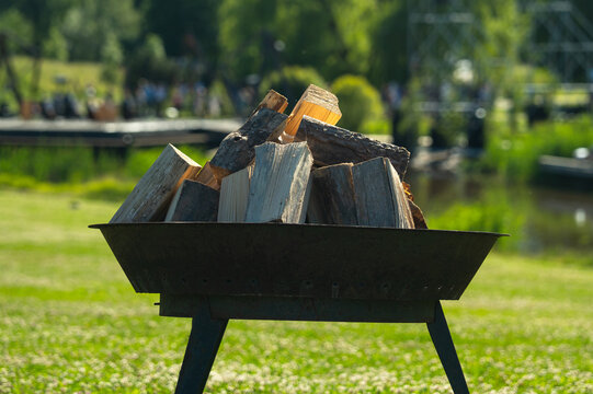 Riga, Latvia - 20 June 2026: View of a metal fire pit filled with stacked firewood in Victory Park during the Midsummer celebration.
