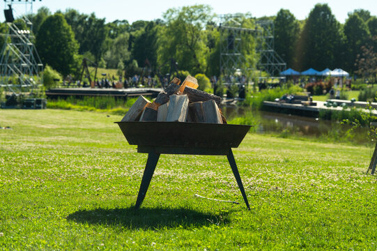 Riga, Latvia - 20 June 2026: View of a metal fire pit prepared for a traditional Midsummer celebration in Victory Park, surrounded by lush green grass and park scenery.