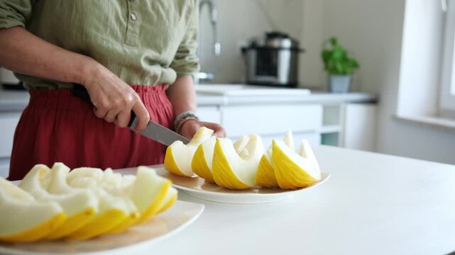 Woman Cutting Melon Into Pieces In The Kitchen Close-Up
