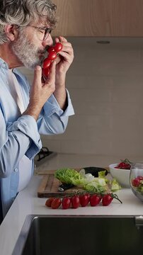 Mature man smelling and preparing fresh vegetable salad