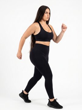 Confident woman in athletic pose with raised fist against white background for fitness and empowerment content