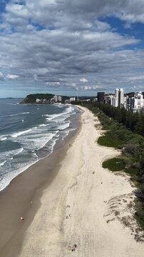 Burleigh Heads drone flight along the beach with the city skyline beyond, Gold Coast, Queensland Australia - vertical video