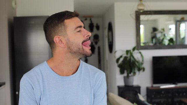 Man sticking out his tongue and trying hard to touch the tip of his nose without success.
