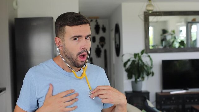 Man putting on a stethoscope at home to listen to his own heart with an anxious expression.