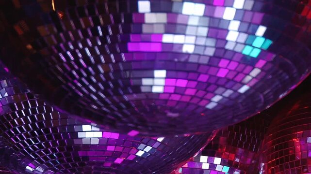Sparkling disco balls hang suspended, catching and dispersing brilliant green, blue, and red light across a festive evening gathering. The radiant glow transforms the space into a vibrant celebration.