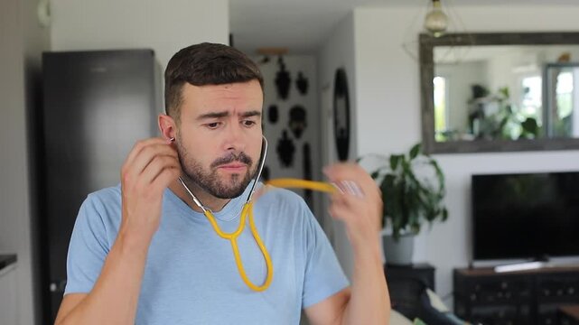 Man putting on a stethoscope at home to listen to his own heart with an anxious expression