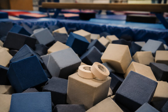 A pile of soft foam cubes in a gymnasium pit with athletic tape on top.