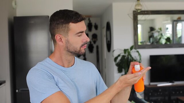 Man applying a large amount of sunscreen from an orange bottle and getting a white layer all over his face.